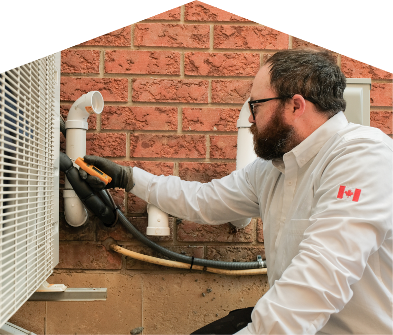 Limcan HVAC specialist checking insulated piping on a heat pump unit beside a brick wall during a diagnostic service.